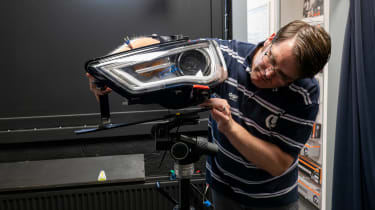 A car headlight being fitted to a stand 